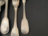 four forks and a spoon on a black table