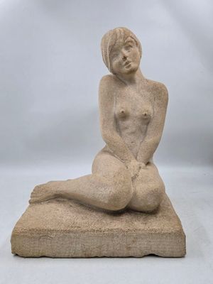 sculpture représentant une femme nue assise sur un coussin, sur fond blanc