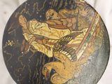 a black and gold plate with a picture of a man on a boat