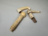une paire de cannes en ivoire sculpté avec des poignées en bois, posées sur une surface blanche