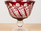 a red glass bowl sitting on top of a wooden table