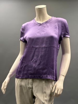Le mannequin porte une chemise violette et un pantalon kaki.