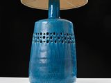 a blue vase with a lamp on a white table