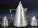 three silver coffee pots and a teapot on a table