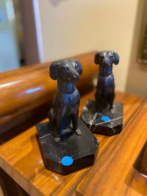 two statues of dogs sitting on top of a wooden table