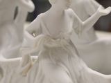 a white statue of a woman sitting on a table