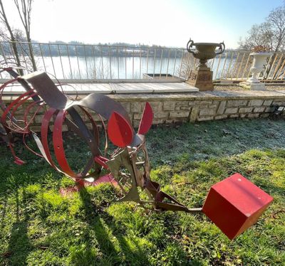 a metal sculpture that is on the grass by the water