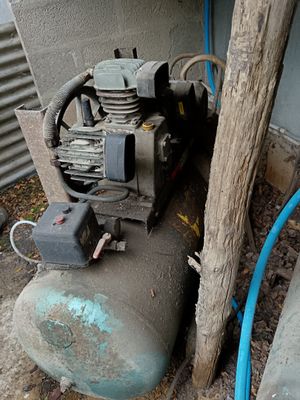 un compresseur d'air posé par terre à côté d'un arbre