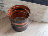 a wooden barrel sitting on the floor next to a brick wall