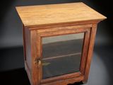 une vieille armoire en bois avec une porte vitrée sur fond noir