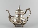 a silver teapot with a handle and a handle on a stand