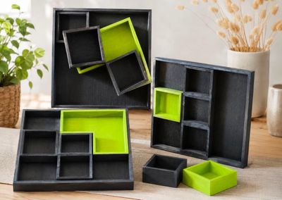 three black and green boxes are sitting on a table next to a potted plant