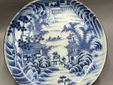 a blue and white plate with a landscape scene on it