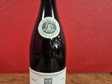 une bouteille de vin posée sur une table devant un mur rouge
