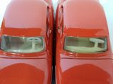 two red toy cars sitting side by side on a white surface