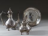 deux théières en argent et une assiette en argent posées sur une table