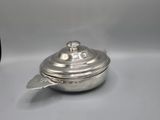 an old silver pot with a lid and a spoon on a table