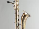 an old silver saxophone sitting on top of a wooden stand
