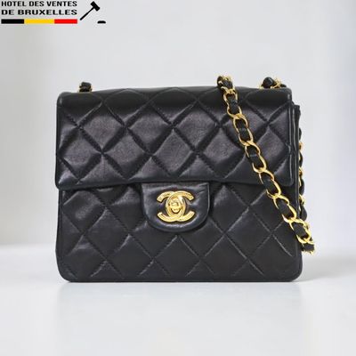 un sac Chanel noir muni d'une chaîne dorée, posé sur une table blanche