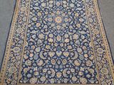 un tapis bleu bordé d'or posé sur un sol gris