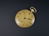 une montre de poche en or posée sur une surface noire