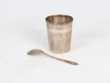 a silver cup with a spoon next to it