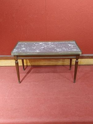 une petite table avec un plateau en carrelage posée sur un tapis rouge