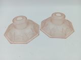 une paire de bougeoirs en verre rose posés sur une surface blanche