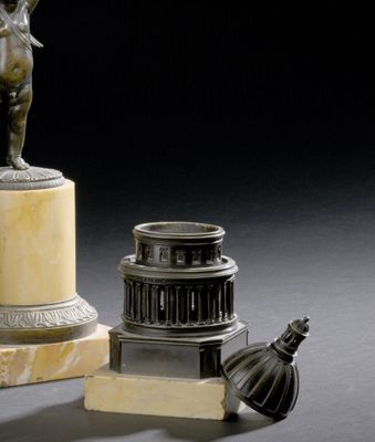 une statue représentant un homme debout sur un socle, à côté d'une lampe
