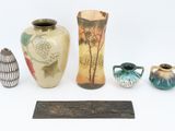 four vases and a plaque on a white surface