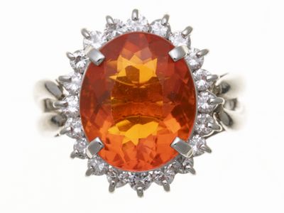 une image représentant une bague ornée d'une pierre orange entourée de diamants blancs