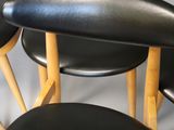 four black leather stools with wooden legs and a black seat