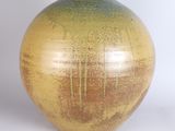 a yellow and green vase sitting on a white surface