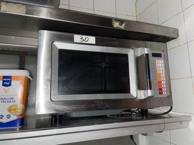 a microwave that is sitting on a shelf in a kitchen