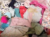 a pile of clothes that is sitting on a bed