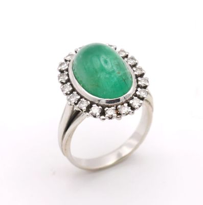 a close up of a ring with a green stone surrounded by diamonds