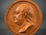 a close up of a bronze medal with a man ' s face on it