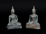 deux statues de bouddhas sont assises sur une surface noire