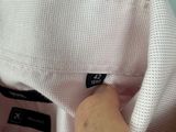 someone is holding a white shirt with a black label on it