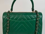 a green handbag with a chain strap on a white background