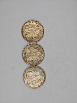 three gold coins sitting on top of each other on a white surface