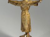 a gold statue of a woman holding her arms out in the air