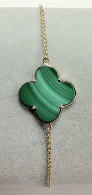 a close up of a bracelet with a green flower on it