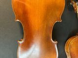 two antique violin ' s on display in a museum, one of which is missing a bow
