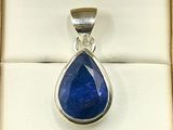 blue sapphire tear shaped pendant in a box on a white background