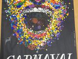 une photo d'une affiche posée sur une table en bois, sur laquelle figure une image représentant un carnaval