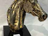 gold horse head sculpture on black base on white background