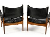 two black leather chairs with wooden legs and black cushions