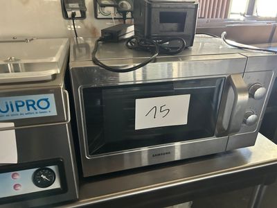 un micro-ondes posé sur un plan de travail, avec une pancarte dessus