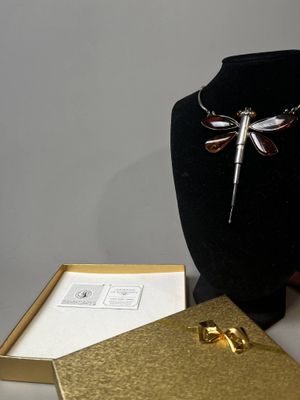 un collier orné d'une libellule, posé à côté d'un coffret à bijoux